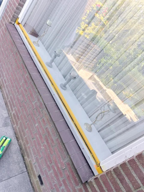 Onderregel van een vast raam — Reparatiewerk aan de onderzijde van een groot raam; de afwerking is nog in uitvoering.