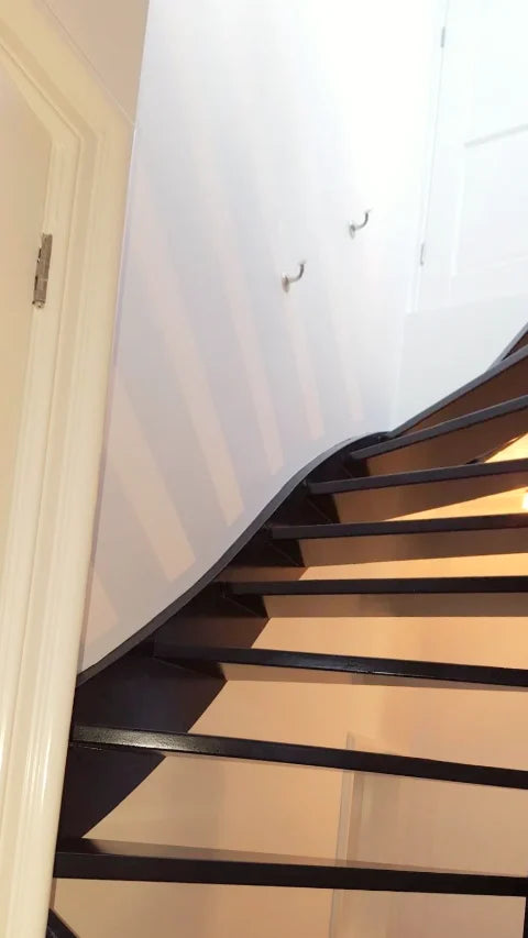 Een donker geschilderde trap — Donkere afwerking op houten treden, trapboom en leuning.