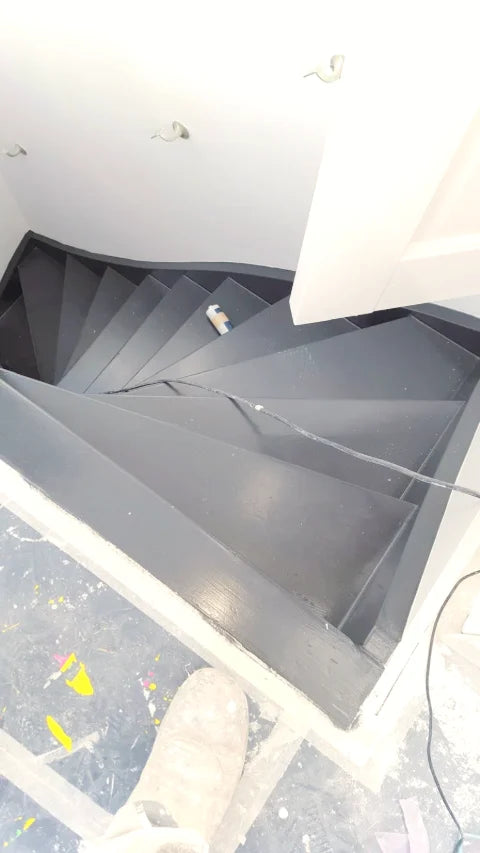 Een donker geschilderde trap — Donkere afwerking op houten treden, trapboom en leuning.