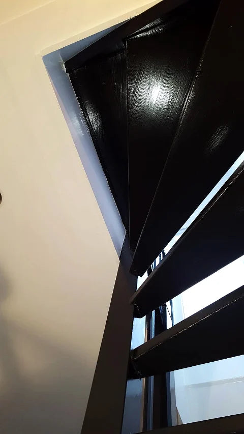 Een donker geschilderde trap — Donkere afwerking op houten treden, trapboom en leuning.