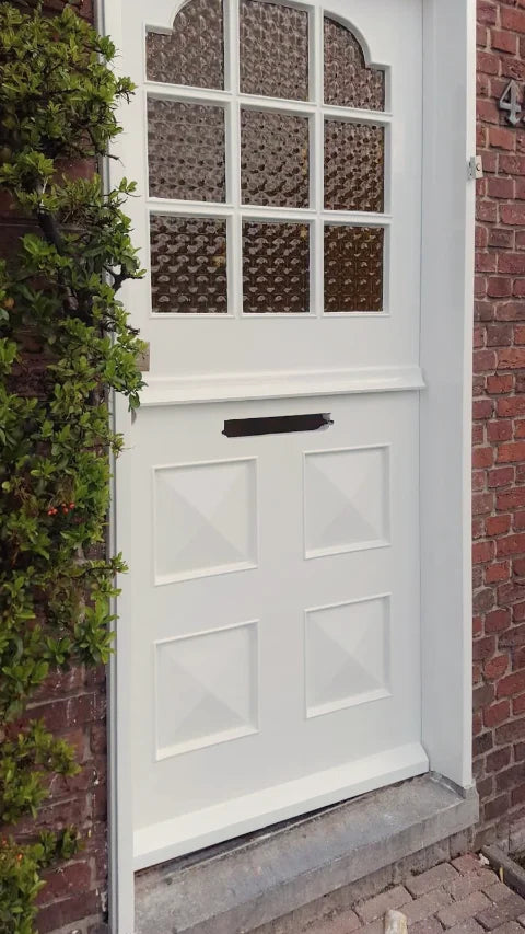 Witte voordeur en kozijn na het schilderwerk, vanuit een andere hoek.