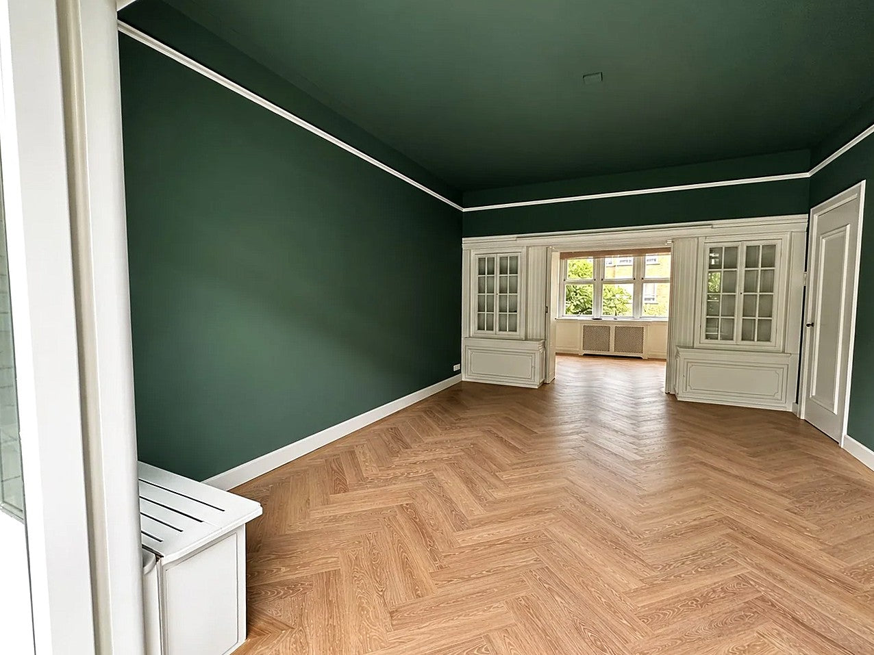 Diepgroen geschilderde wanden en plafond met witte paneeldeuren, sierlijst en visgraatvloer — eigen werkfoto van Renovra Bouw