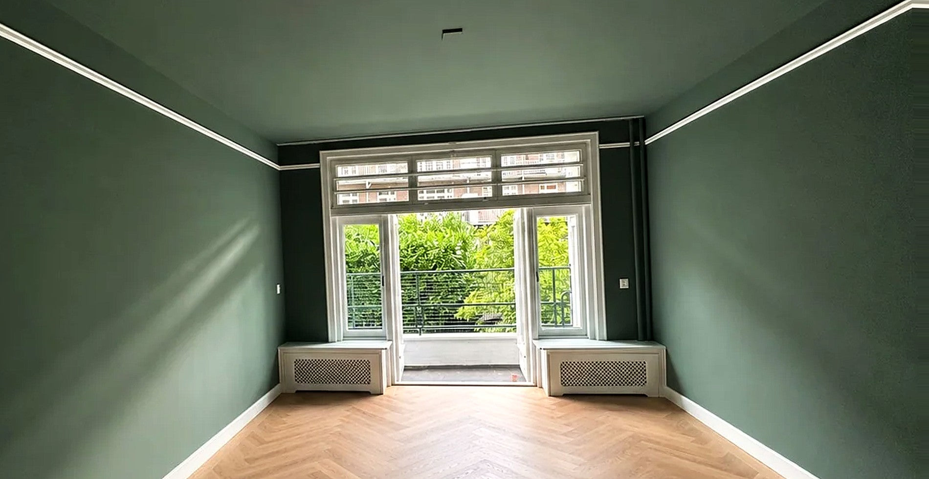Groen geschilderde kamer met wit houtwerk en visgraatvloer — eigen werkfoto van Renovra Bouw