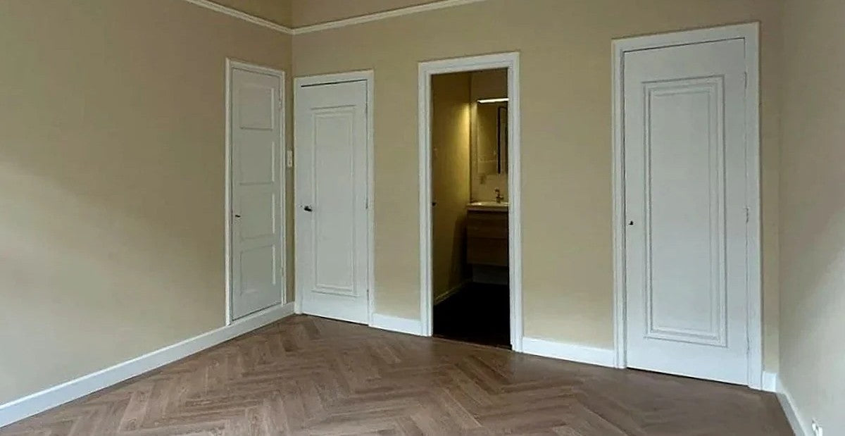Beige geschilderde kamer met witte paneeldeuren en visgraatvloer — eigen werkfoto van Renovra Bouw